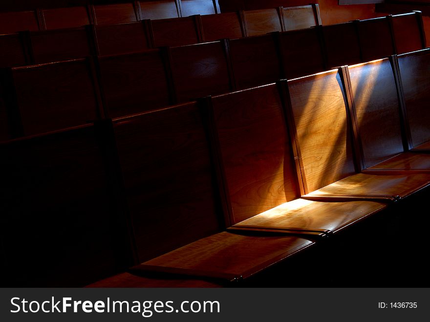 Rows of church pews with stream of light illuminating a seat