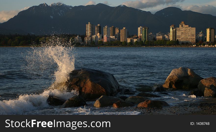 Wave hitting rock with vancouver in background. Wave hitting rock with vancouver in background