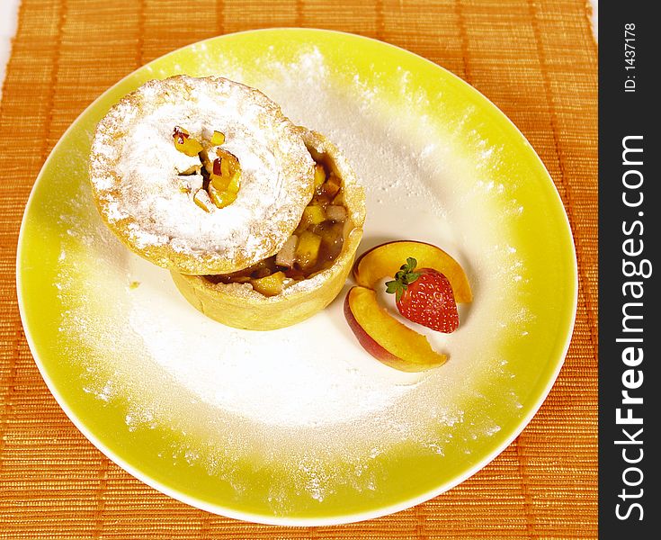 Homemade apple pie with powdered sugar and peach and strawberry decoration