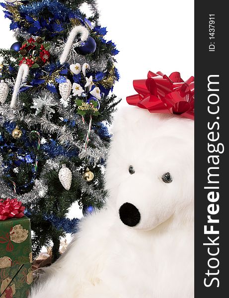 A christmas tree with wrapped presents around the base and a huge stuffed bear. A christmas tree with wrapped presents around the base and a huge stuffed bear