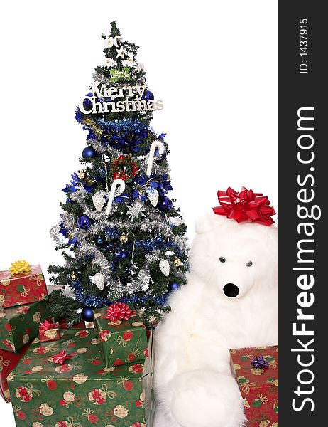A christmas tree with wrapped presents around the base and a huge stuffed bear. A christmas tree with wrapped presents around the base and a huge stuffed bear