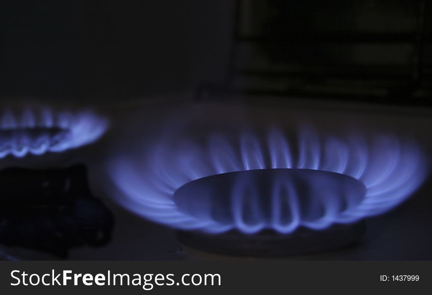 The flame of a gas-stove in the dark of a kitchen. The flame of a gas-stove in the dark of a kitchen