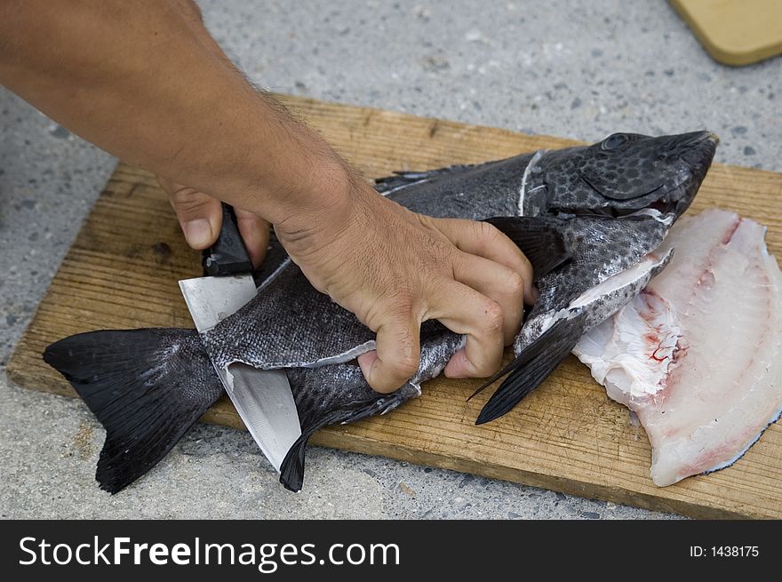 A man cutting and preparing a fish for eating. A man cutting and preparing a fish for eating