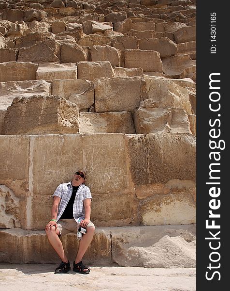 Tourist sitting at the bottom of the pyramides of Giza