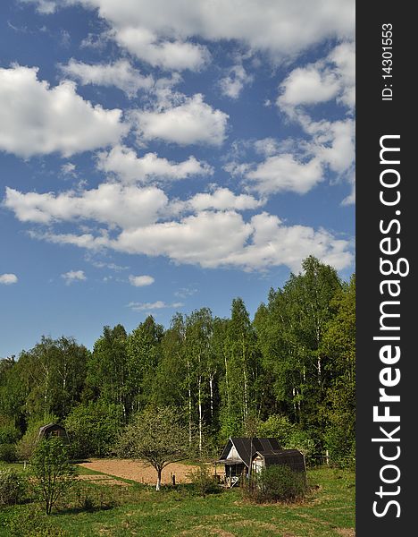 Landscape with old country wooden shacks, spring forest and cloudy sky. Landscape with old country wooden shacks, spring forest and cloudy sky