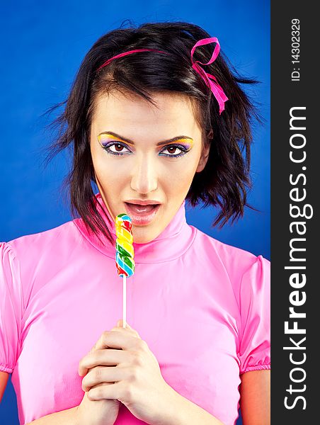 Young beautiful woman posing with lollipop on blue background. Young beautiful woman posing with lollipop on blue background