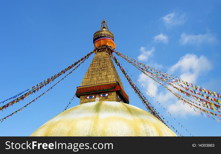 Bodhnath stupa in kathmandu with buddha eyes and prayer flags on clear blue sky background