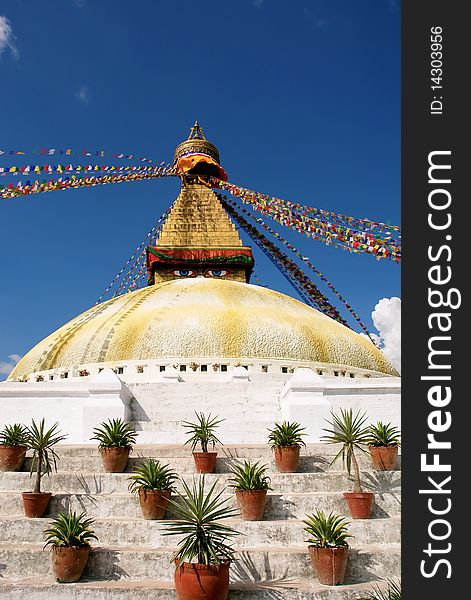 Bodhnath stupa in kathmandu with buddha eyes and prayer flags on clear blue sky background