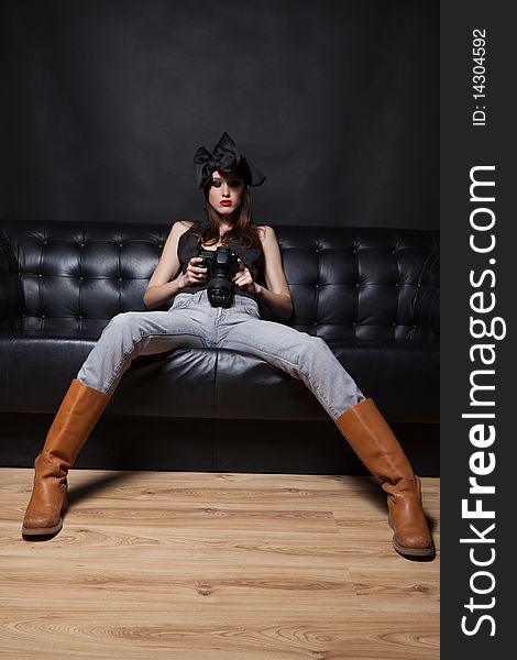 Young glamorous woman on a black sofa with photo camera at hands. Young glamorous woman on a black sofa with photo camera at hands.