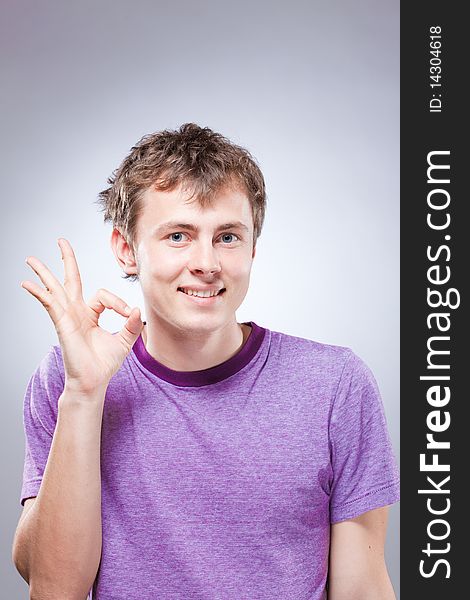 Portrait of handsome smiling young man making an ok sign