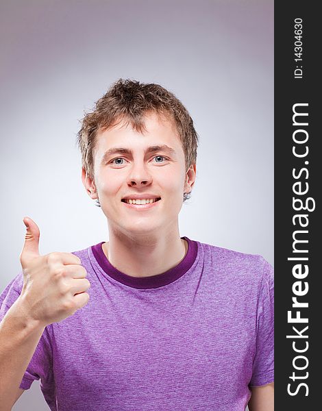 Portrait of handsome smiling young man, thumb up