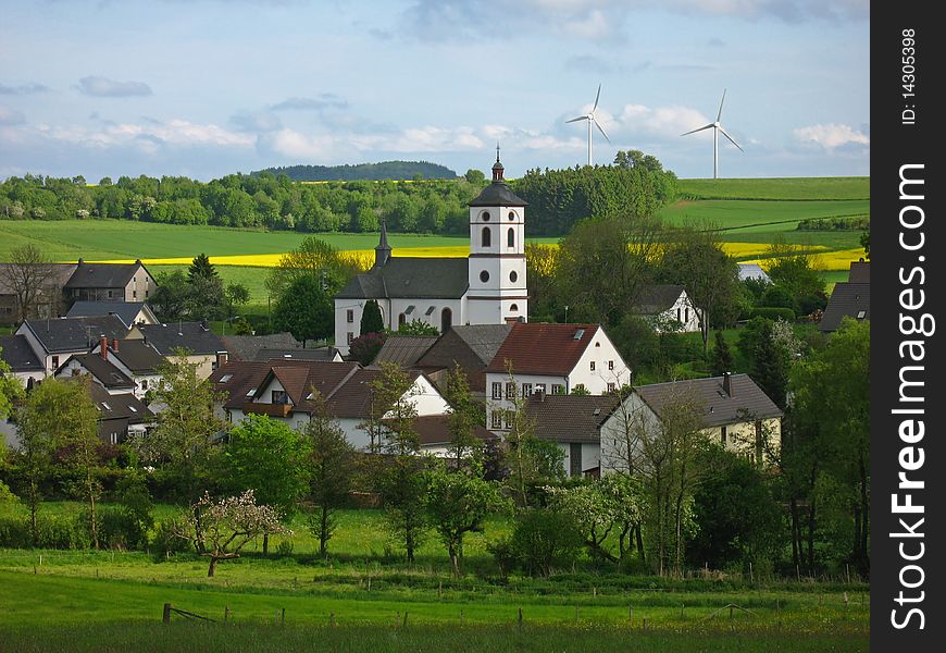 Idyllic village in Germany with rape and wind wheels in the background