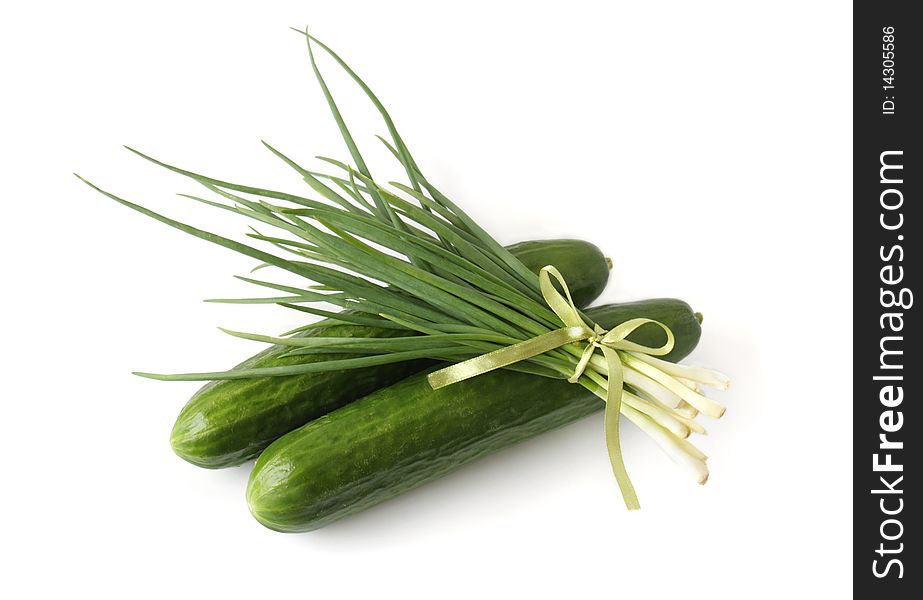 A bunch of green onions and cucumbers on a white background