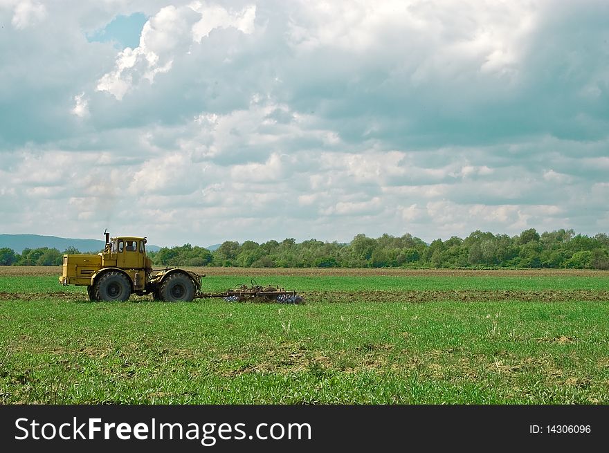 Working tractor under cloudy sky