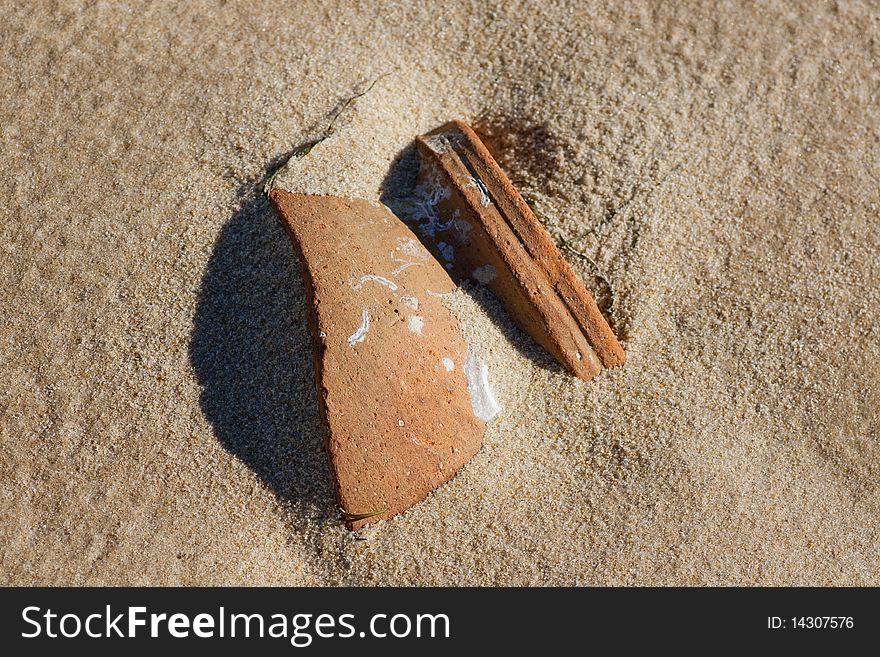 Close view of a broken ceramic pot buried on the sand. Close view of a broken ceramic pot buried on the sand.