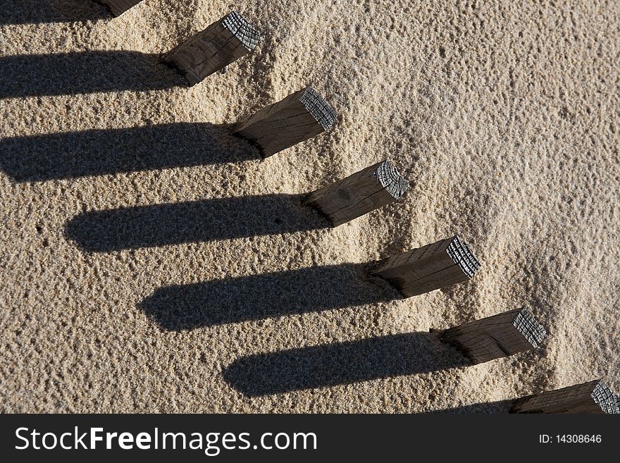 View of a section of a fence buried on the sand making a shadow. View of a section of a fence buried on the sand making a shadow.
