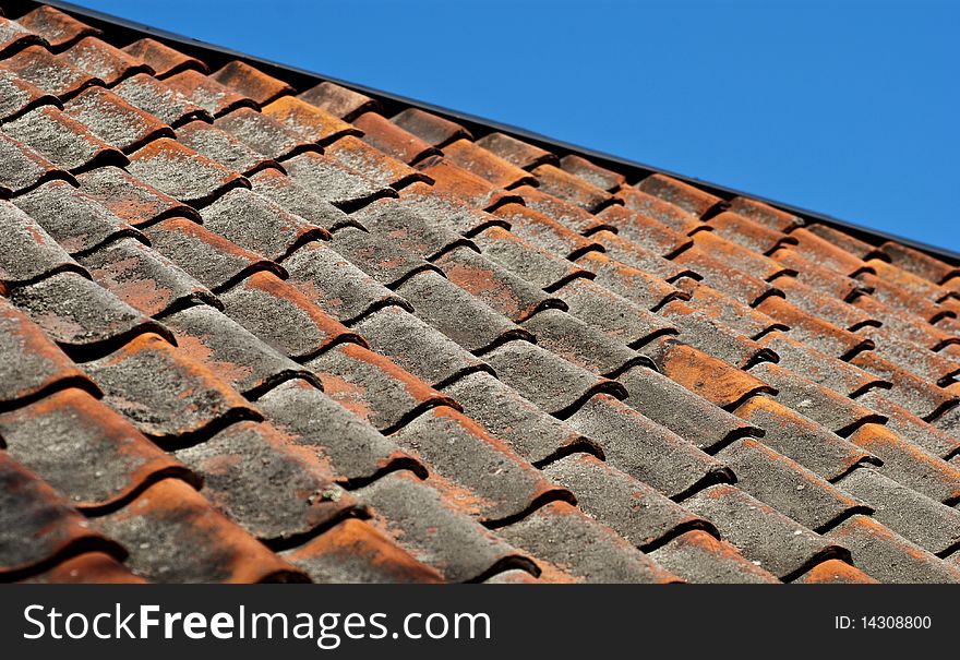 Old tiled roof with blue sky above. Old tiled roof with blue sky above