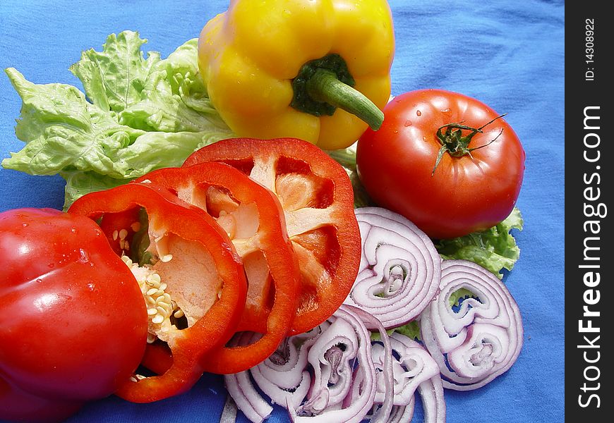 Vegetables: tomatoes, onions, peppers and lettuce on a blue background. Vegetables: tomatoes, onions, peppers and lettuce on a blue background