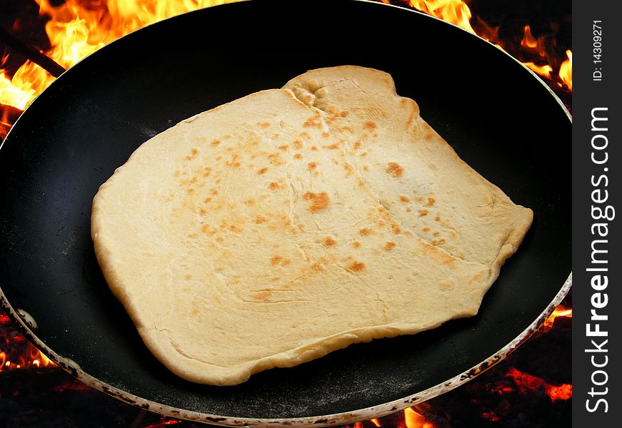 Pita in a black pan on the fire. Pita in a black pan on the fire