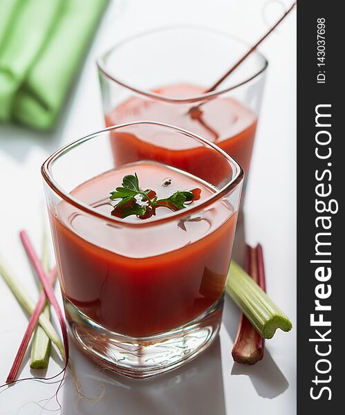 Tomato juice with fresh spices in glasses on a wooden table. Tomato juice with fresh spices in glasses on a wooden table