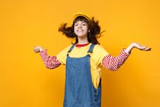 Free Cheerful Girl Teenager In French Beret Denim Sundress Spreading Hands With Fluttering Hair Isolated On Yellow Wall Stock Image - 143057001