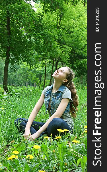 Happy Young Girl Sitting On The Grass