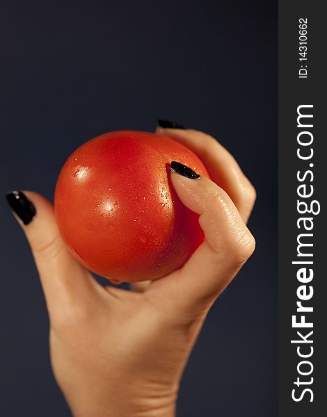 View of a woman's hand holding a red tomatoe. View of a woman's hand holding a red tomatoe.