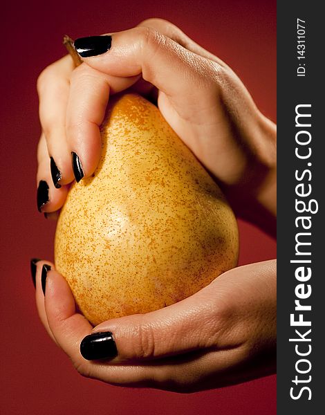 Close up view of two woman hands holding a pear. Close up view of two woman hands holding a pear.
