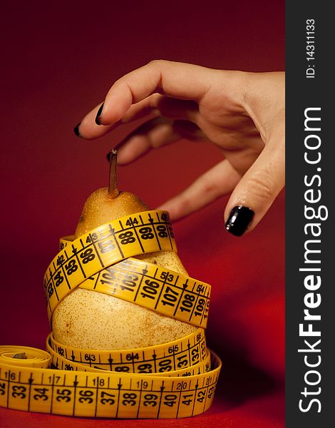 View of a woman's hand trying to grab a pear with measuring tape.