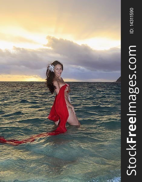 Forty year old woman in the ocean in chiffon at sunrise