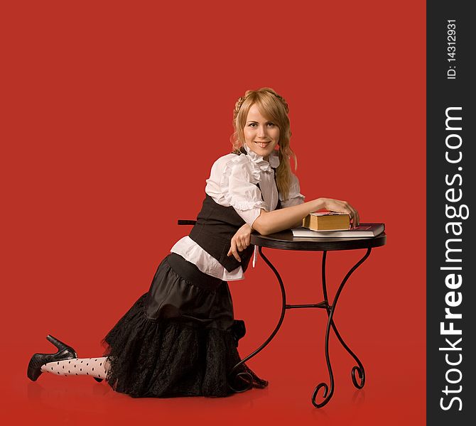 Attractive girl rests on the table with the books - a red background