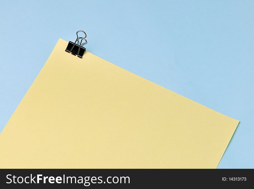 Yellow note and clip in a blue background. Yellow note and clip in a blue background