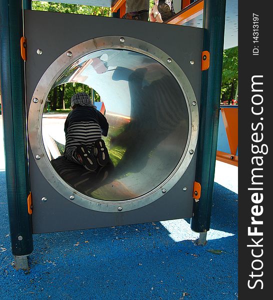 A child going through a tube at the playground. A child going through a tube at the playground