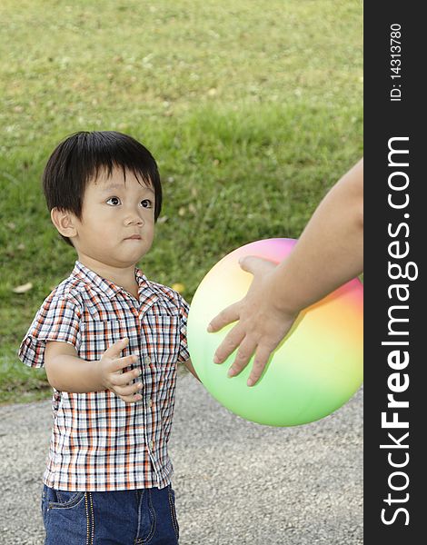 An Asian boy receiving a ball from his mother. An Asian boy receiving a ball from his mother