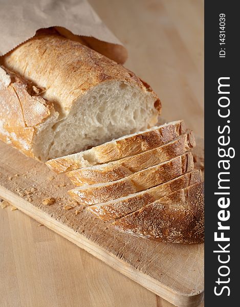 Partially Sliced Loaf of Bread on Wood Cutting Board and in brown paper bag