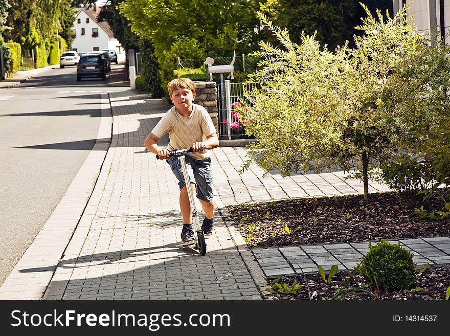 Boy Rides Scooter On The Paveway At A Street