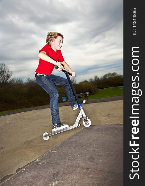 Boy riding a scooter going airborne at a scooter park. Boy riding a scooter going airborne at a scooter park