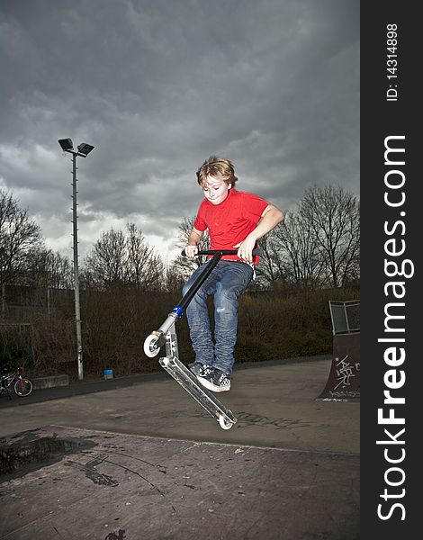 Boy riding a scooter going airborne at a scooter park. Boy riding a scooter going airborne at a scooter park