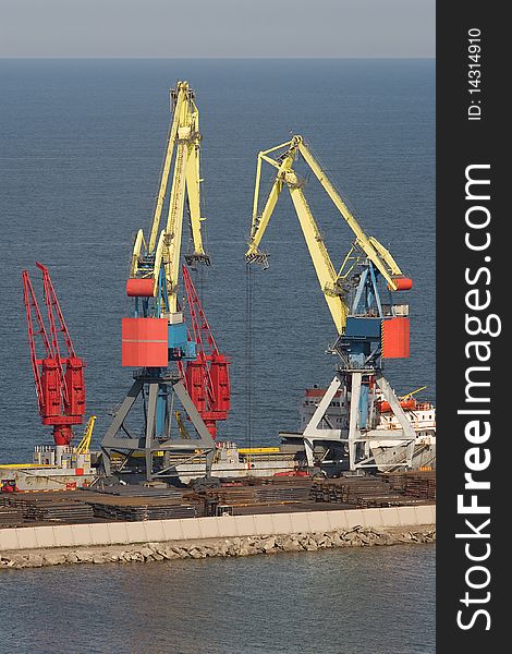 Two heavy industrial cranes working at the commercial dock in the middle of a day. Two heavy industrial cranes working at the commercial dock in the middle of a day