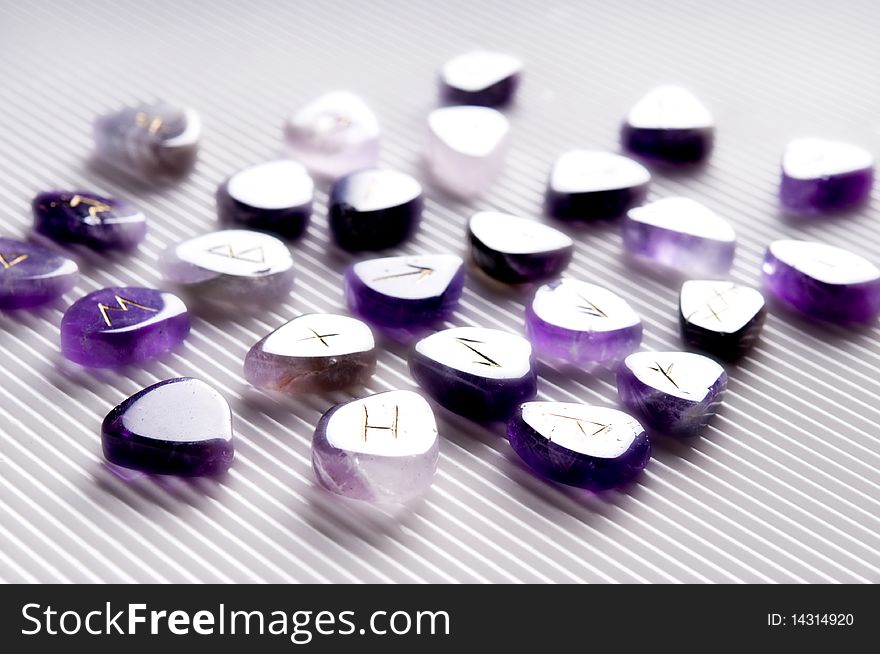 Beautiful violet stones with runes symbols over white background