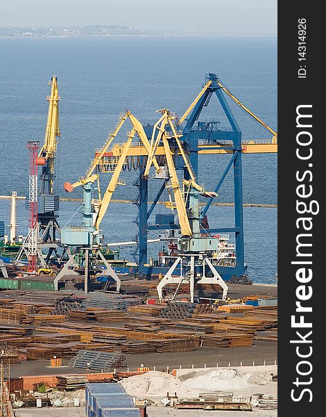 Two heavy duty industrial cranes unloading steel from a tanker ship. Two heavy duty industrial cranes unloading steel from a tanker ship