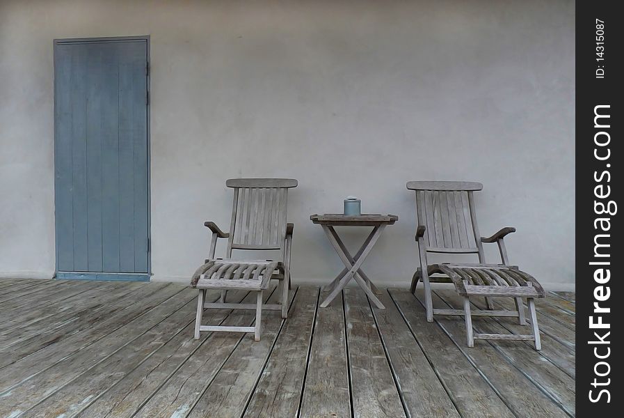 Lounge chair towards plaster wall with a blue door in the back. Photo taken in Furilden on the island og Gotland Sweden. Lounge chair towards plaster wall with a blue door in the back. Photo taken in Furilden on the island og Gotland Sweden.