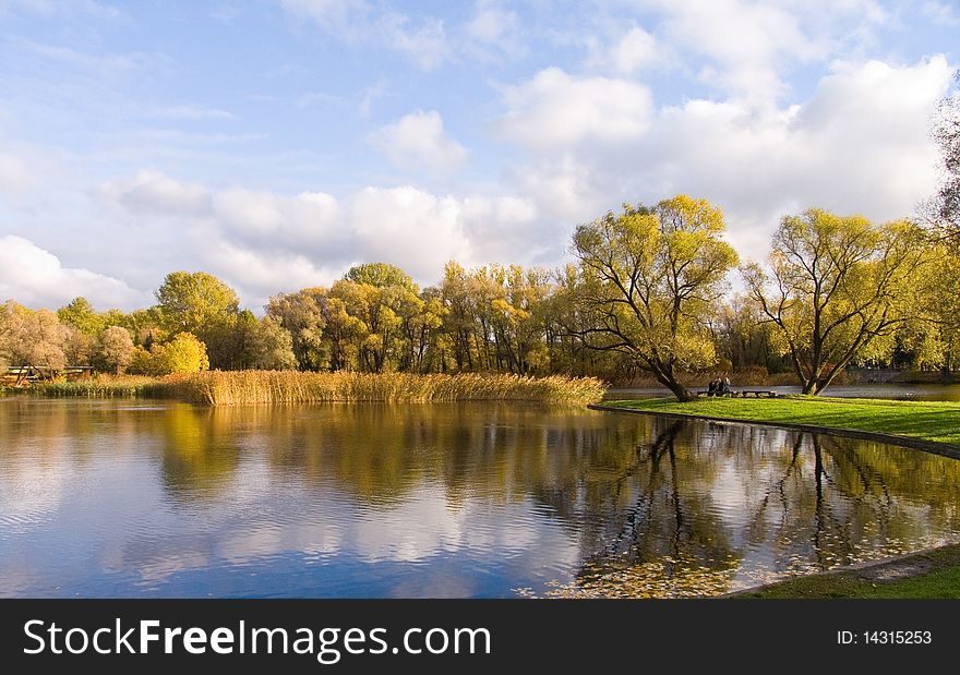 Park in the autumn. Reflexion in water, trees, the sky.