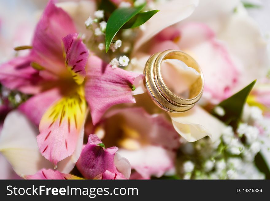 Two gold wedding rings on a flower bouquet