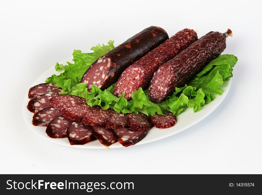 Three sliced sausages with green salad on a white plate. Three sliced sausages with green salad on a white plate