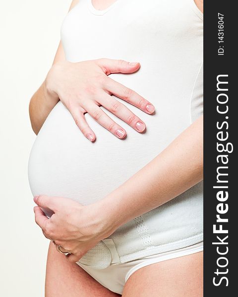 Closeup of a young pregnant woman holding her hands on her tummy