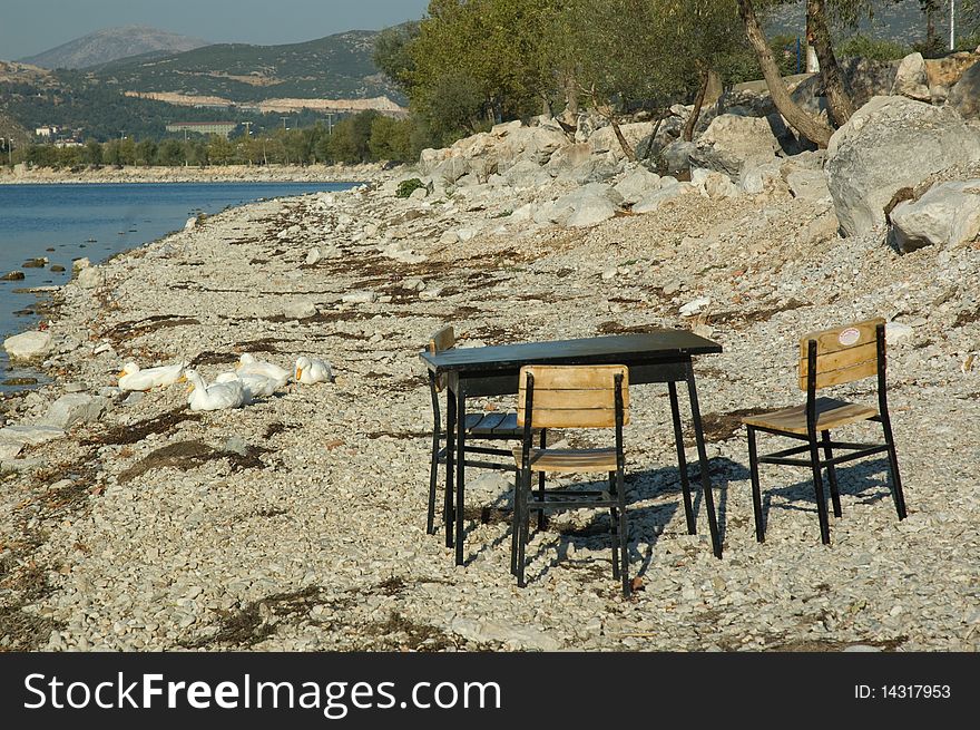 Lake and abandonet seats and table on the beach