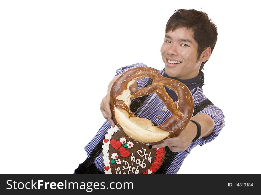 Asian man dressed with Bavarian Lederhose holds an Oktoberfest pretzel in camera. Isolated on white. Asian man dressed with Bavarian Lederhose holds an Oktoberfest pretzel in camera. Isolated on white.
