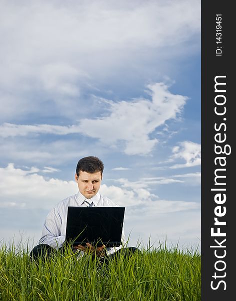 Businessman working in a meadow with laptop. Businessman working in a meadow with laptop