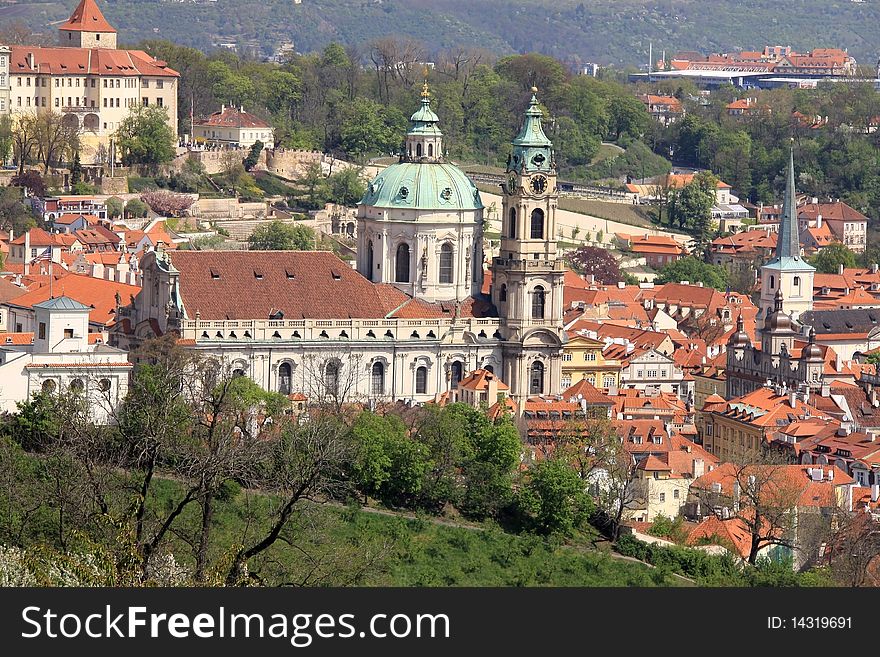 View on PragueÂ´s St. NicholasÂ´ Cathedral with flowering trees and green grass